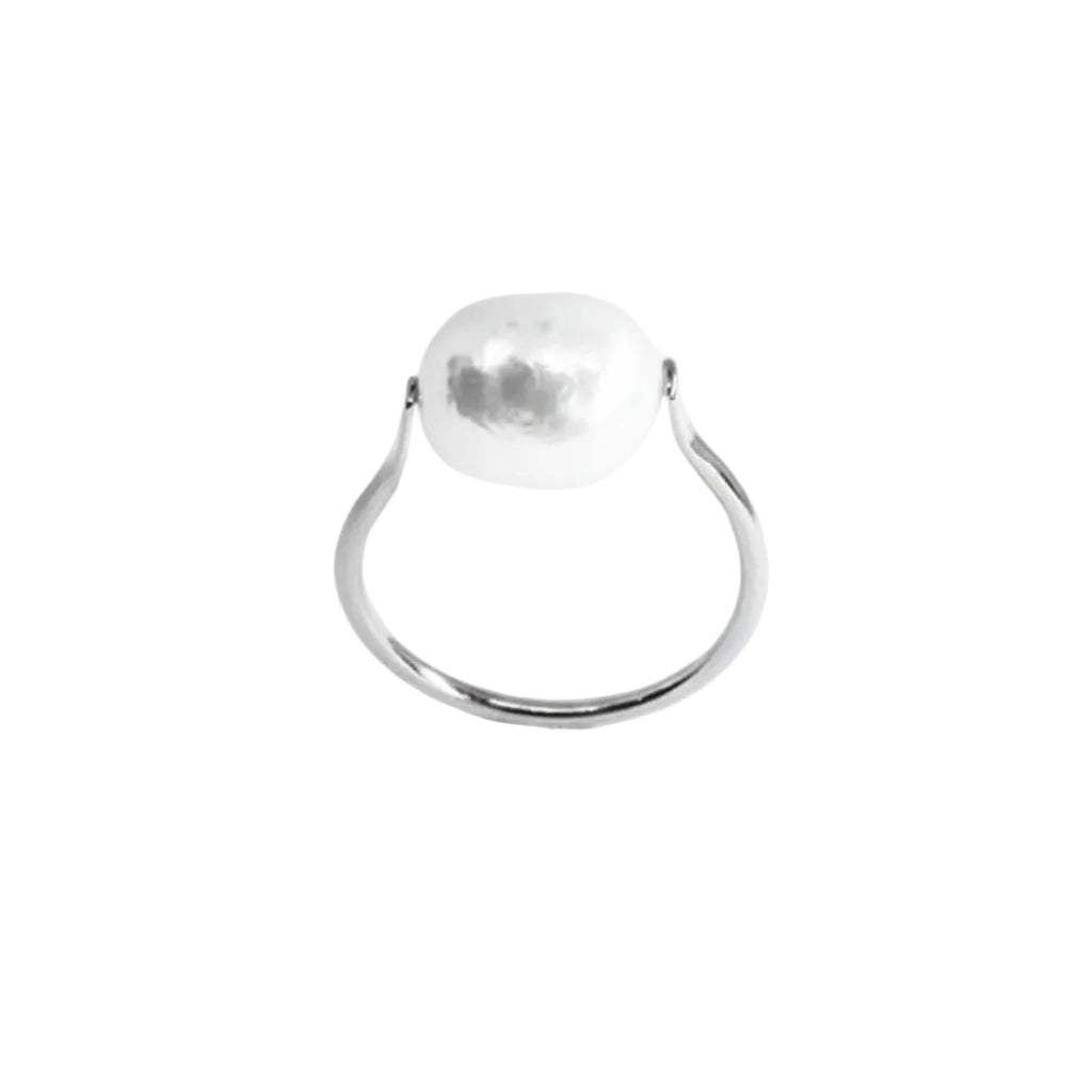 A minimalist silver ring featuring a large, irregularly shaped, hammered white stone in a prong setting, shown against a plain white background.