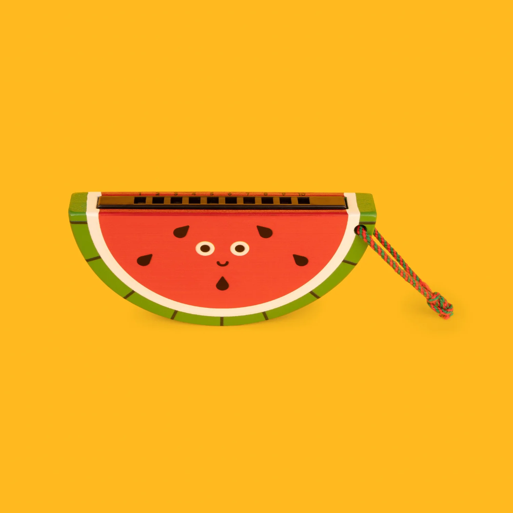A watermelon-shaped accessory with a smiling face, featuring a red center, green rind, and a small multicolor hanging cord, shown on a solid yellow background.