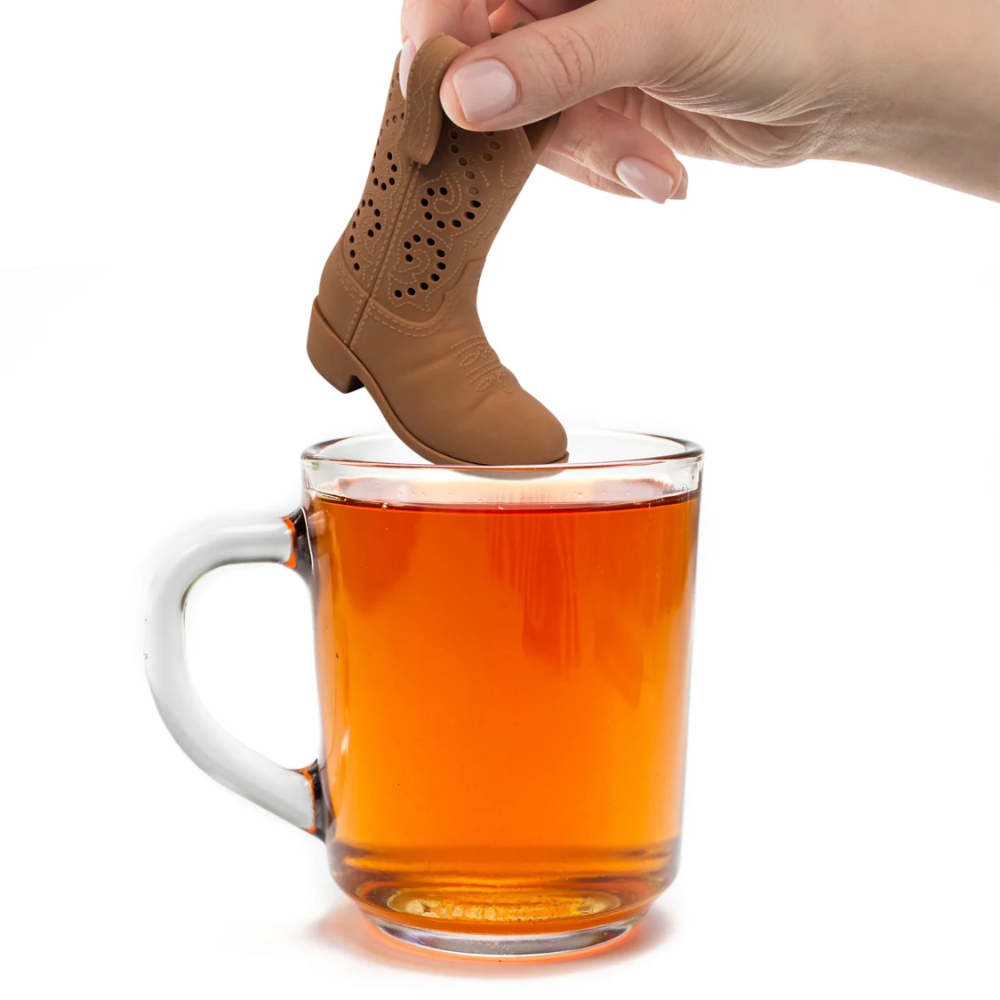 Tea infuser shaped like a cowboy boot being placed into a glass of tea.