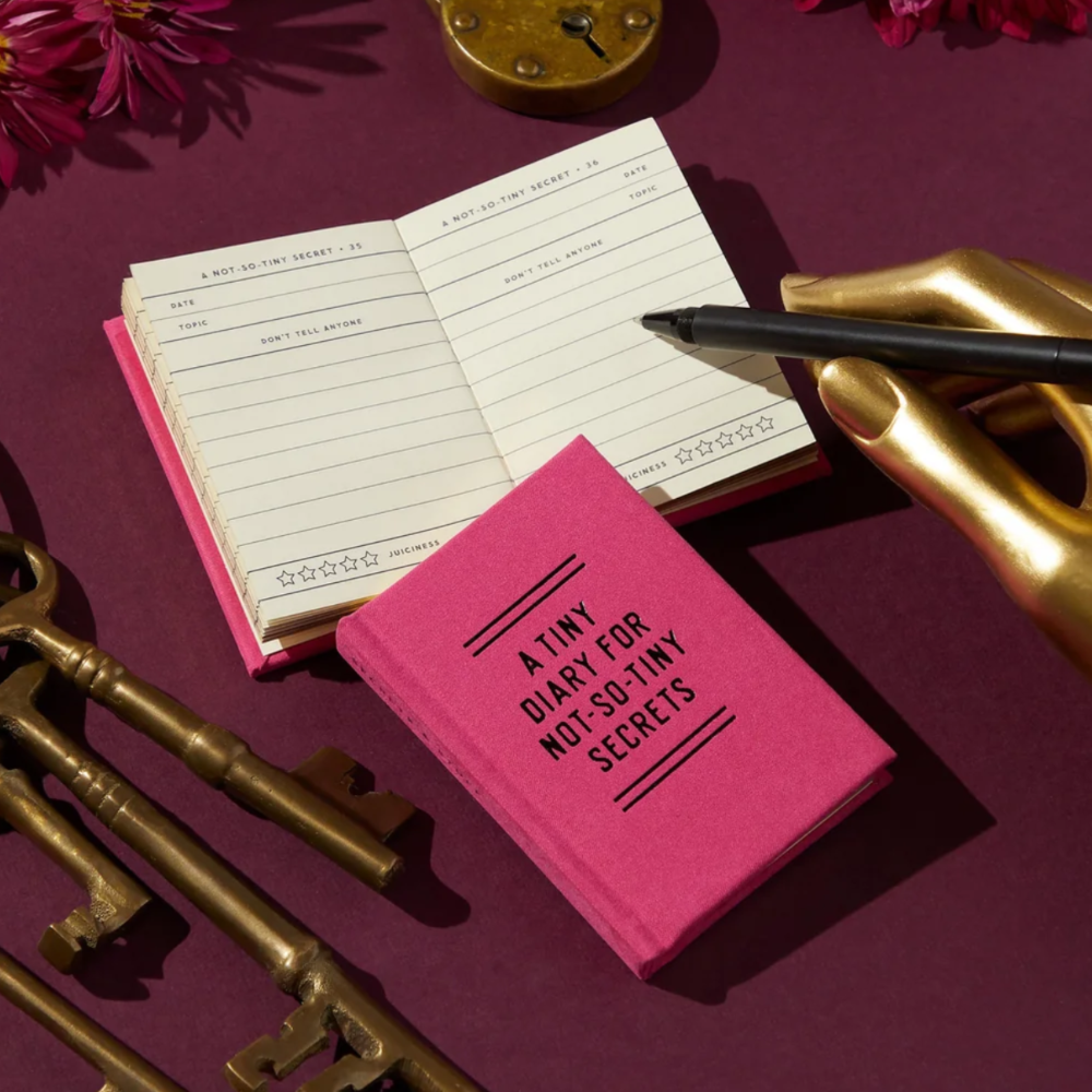 Pink notebook with text, open notebook, gold pen, and vintage keys on a purple background