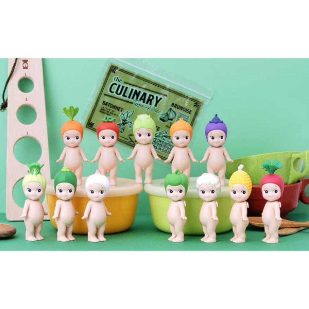 Colorful baby figurines with vegetable-themed hats on a green background