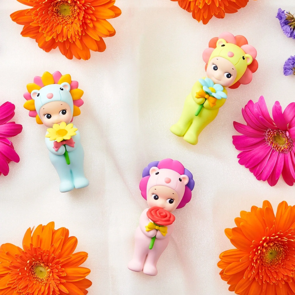 Colorful Sonny Angel figurines with floral designs on a white background with flowers.