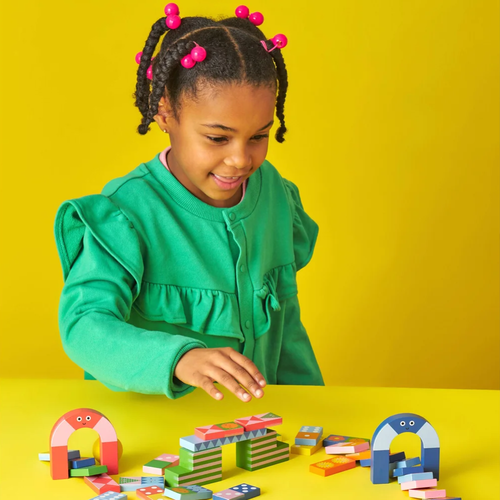 Child playing with colorful building blocks on a yellow background