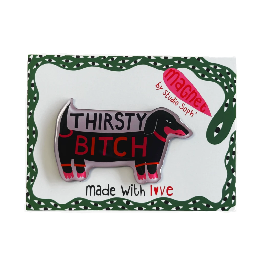 A novelty enamel pin shaped like a dachshund with the text 'THIRSTY BITCH' in red and white, displayed on its green and white backing card which reads 'made with love' and features a pink 'Machee by Studio Soph' logo.
